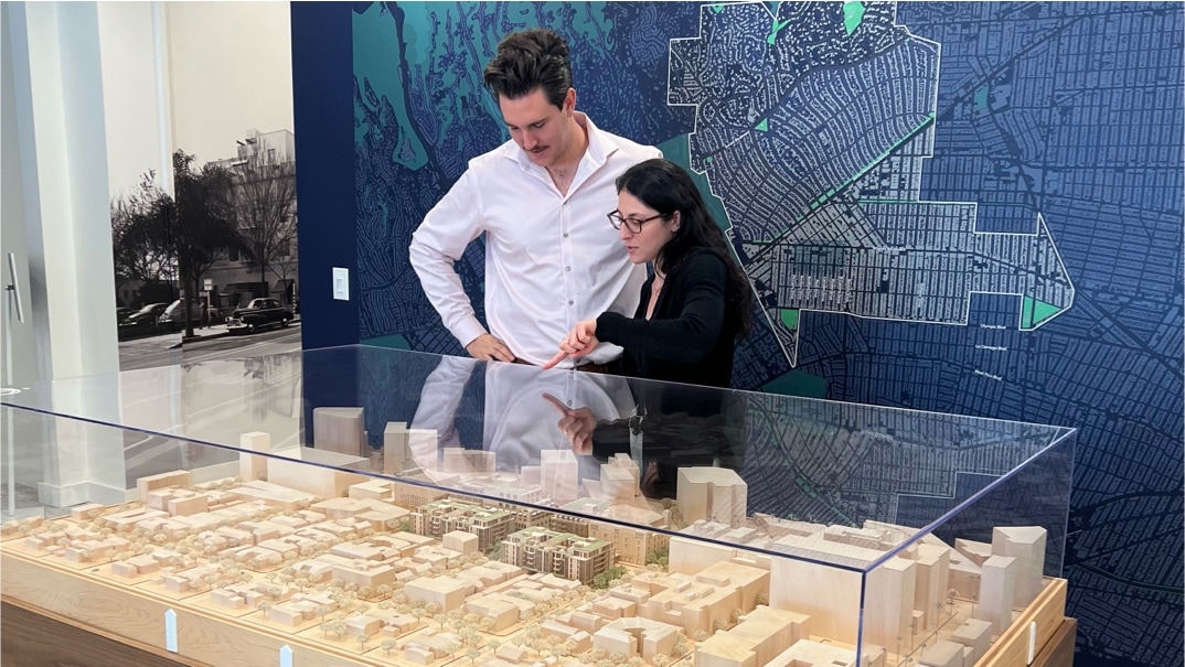 2 young adults looking at the model of the 9600 Wilshire project